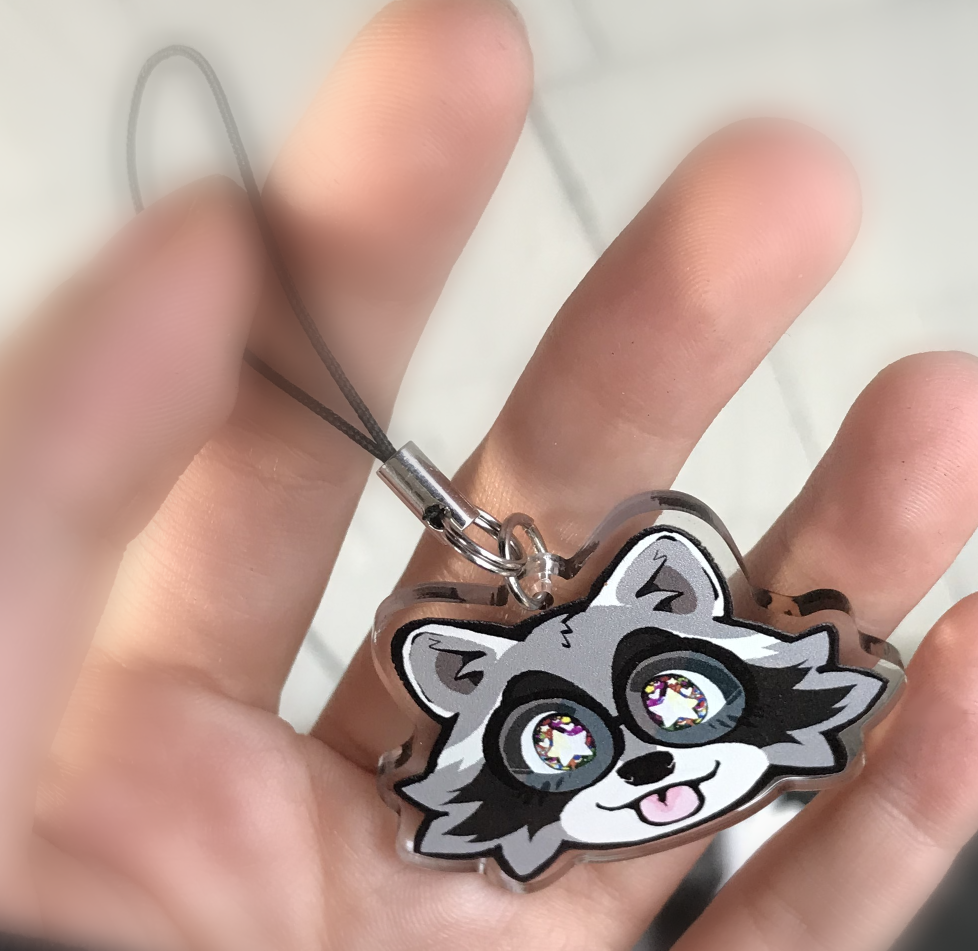 The Boba-tan raccoon blep charm, photographed while being held in the photographer's hand.